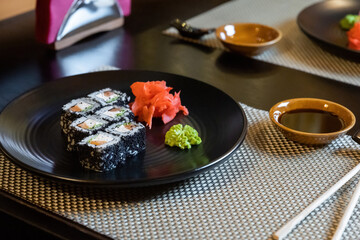 Close-up of fresh rolls and sushi set, with salmon, sprinkled with black caviar. Plate in the middle of the composition