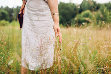 Mental health. Woman walking in meadow feeling harmony with nature and balance touching grass. Healthy lifestyle