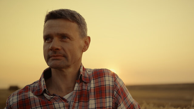 Happy farmer standing in wheat field at golden sunset hour. Agronomist portrait 