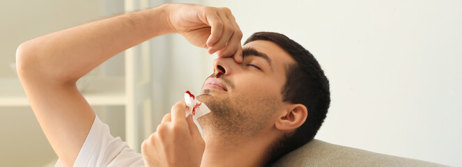 Young man with nosebleed at home