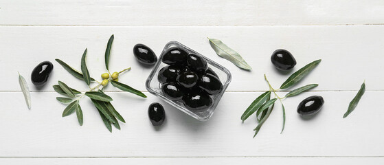Naklejka na ściany i meble Bowl of tasty black olives on white wooden background, top view