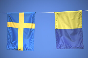 Zwei blau, gelbe schwedische Fahnen, Wimpel, Banner oder Flaggen hängen auf einer Schnur. Im Hintergrund ist der blaue Himmel zu sehen. Ukraine.