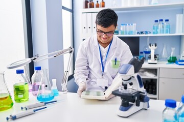 Down syndrome man wearing scientist uniform working at laboratory