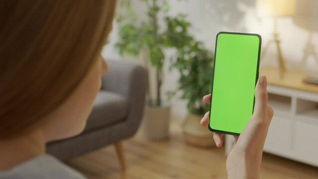 Point of View of Woman on Living Room Holding Chroma Key Green Screen Smartphone Watching Content Without Touching or Swiping. Girl Using Mobile Phone, Browsing Internet, Watching Content.