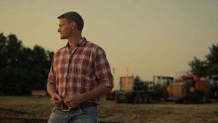 Farmer looking wheat field at golden summer sunset. Modern agribusiness concept