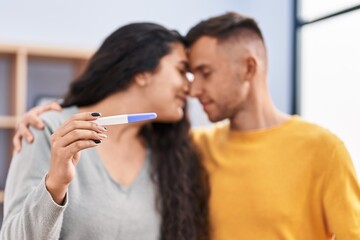 Man and woman couple holding pregnancy test at bedroom