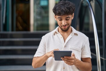 Young arab man smiling confident using touchpad at street