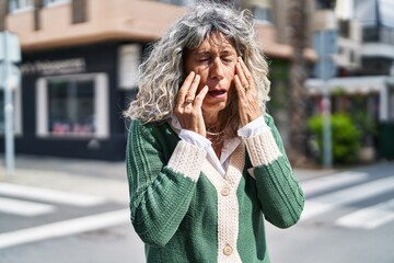 Middle age woman suffering for headache standing at street