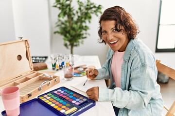 Obraz na płótnie Canvas Middle age hispanic artist woman smiling happy drawing at art studio.