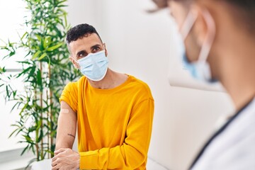 Fototapeta premium Two man doctor and patient put band aid on arm at clinic