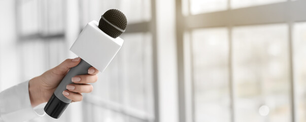 Female journalist with microphone indoors