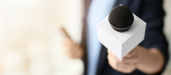 Female journalist with microphone in office, closeup