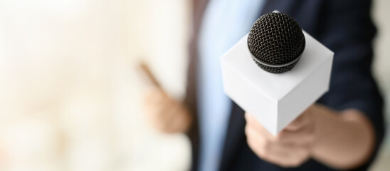 Fototapeta premium Female journalist with microphone in office, closeup