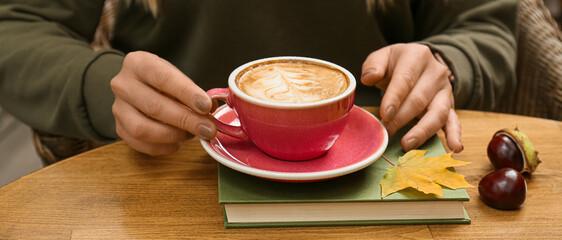 Woman drinking hot coffee at home on autumn day, closeup