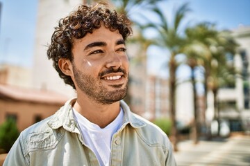 Handsome hispanic man with beard smiling happy outdoors on a sunny day