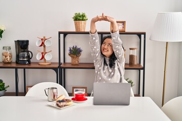 Young chinese woman stretching arms working at home