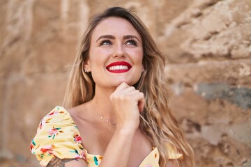 Young beautiful hispanic woman smiling confident looking to the side over isolated stone background