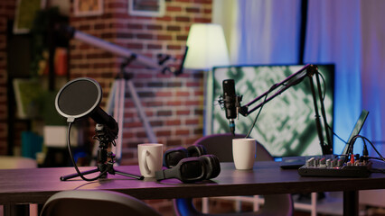 Closeup of headphones and professional microphone on empty vlogger desk ready for live talk show...