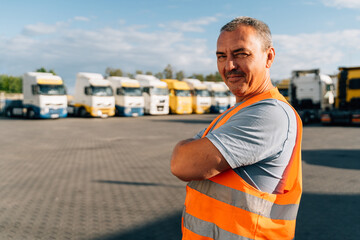 Portrait of caucasian mature man on semi-truck vehicles parking background. Truck driver worker 