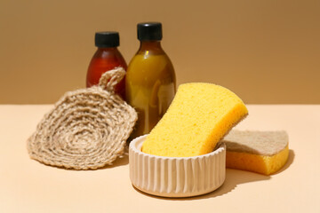 Fototapeta na wymiar Household sponges and bottles on color background