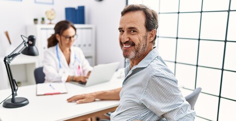 Middle age man and woman wearing doctor uniform having medical consultation at clinic
