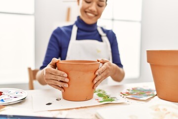 Young latin woman smiling confident making clay pot at art studio