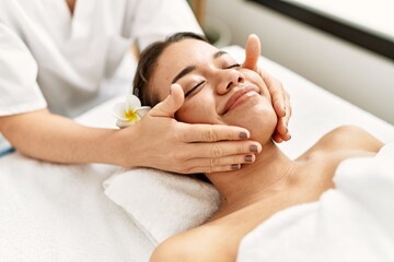 Fototapeta na wymiar Young latin woman relaxed having face massage at beauty center