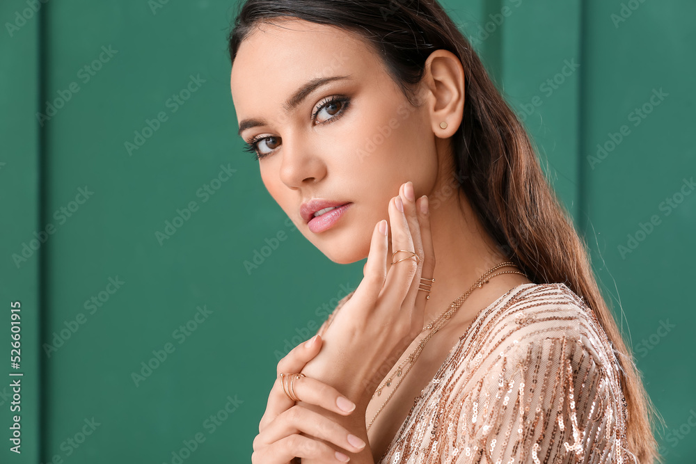 Wall mural Beautiful young woman with stylish jewelry on green background - Wall murals