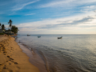 Beautiful view of an idyllic tropical sandy beach with three fisher boats in the sea in Vietnam