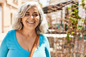 Middle age grey-haired woman smiling happy standing at the city.