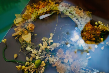 Dry compositions and bouquets of flowers and plants for the interior lie on a white wooden table. Flower wreath