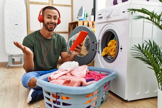 African american man doing laundry listening to music celebrating achievement with happy smile and winner expression with raised hand