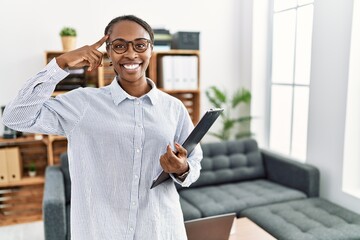 African woman working at psychology clinic smiling pointing to head with one finger, great idea or...