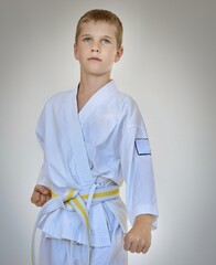 a boy in a white kimono stands barefoot on a white background