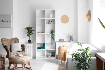 Interior of cozy living room with rattan table, armchair and shelving unit