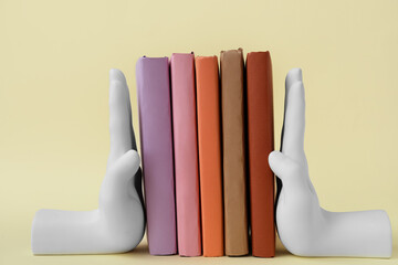 Books with stands in shape of hands on beige background © Pixel-Shot