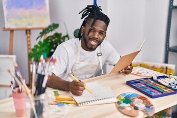 African american woman reading book drawing on notebook at art studio