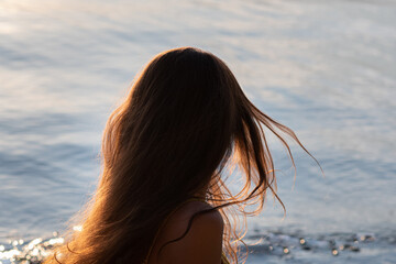 Long hair of a woman close-up develops in the wind against the background of the sea