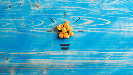 Light bulb made of smashed yellow papers and hand drawn glow