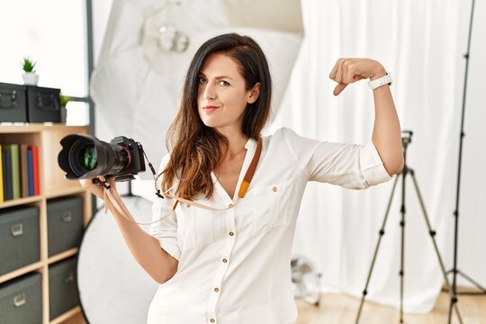 Beautiful caucasian woman working as photographer at photography studio strong person showing arm muscle, confident and proud of power