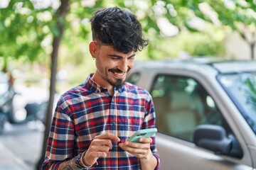 Obraz premium Young hispanic man smiling confident using smartphone at street