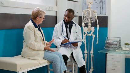 Physician doing medicare consultation with senior patient, meeting in doctor office to do medical...