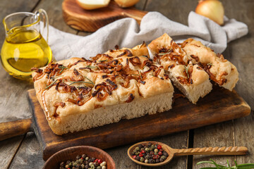 Board of tasty Italian focaccia with roasted onion on wooden table, closeup