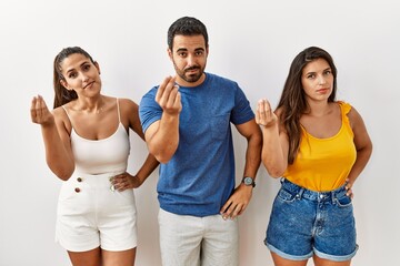 Group of young hispanic people standing over isolated background doing italian gesture with hand and fingers confident expression