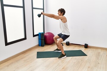 Obraz premium Young hispanic man smiling confident training using kettlebell at sport center