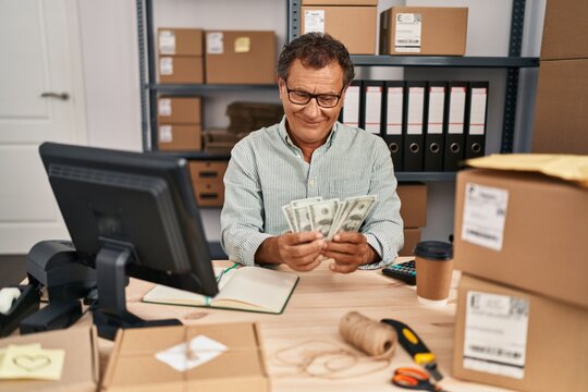 Middle age man ecommerce business worker holding dollars at office