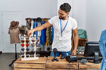 Young arab man shopkeeper touching glasses working at clothing store