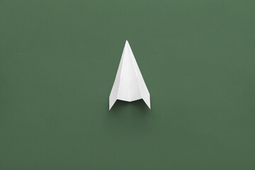 White paper plane on green background