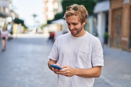 Young man smiling confident using smartphone at street