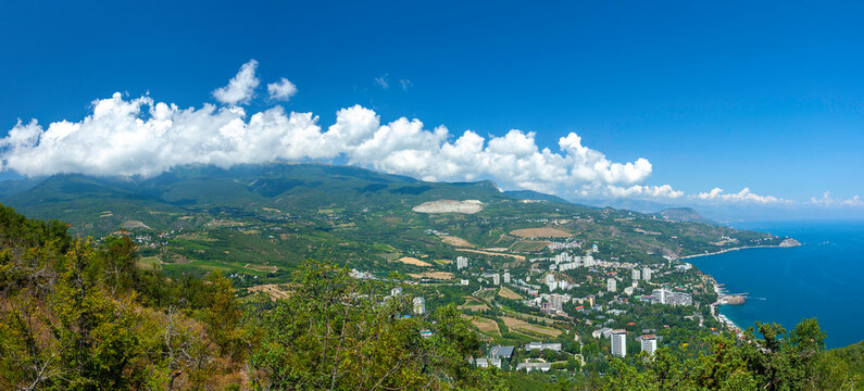 A Panoramic View From Ayu-Dag Mountain On The Cozy Resort Town Of Partenit And Sea Bay In The Black Sea With Its Green Mountains At Background And Blue Sky With Curly Clouds. Partenit,Crimea,Ukraine